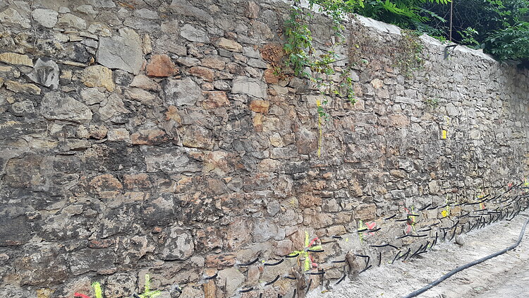 Foto einer alter Stadtmauer aus Stein mit gelben Markierungen