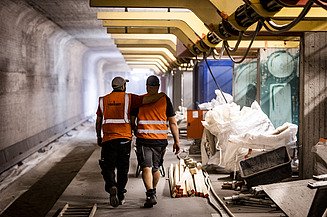 Partnerschaftliches Bauen Foto von zwei Personen mit Warnweste auf einer Baustelle neben Gleisen