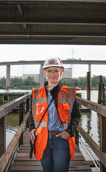 Foto einer Frau in Baustellenausrüstung vor einer Brücke
