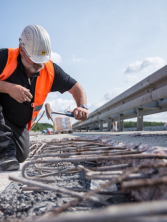Foto einer Person mit Baustellenausrüstung mit einem Hammer in der Hand