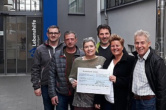 Foto von sechs Personen mit einem Spendencheck in der Hand