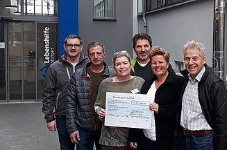Foto von sechs Personen mit einem Spendencheck in der Hand