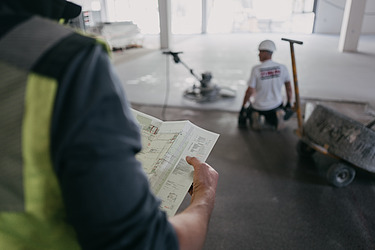 Foto einer Person von hinten mit einem Plan in der Hand 