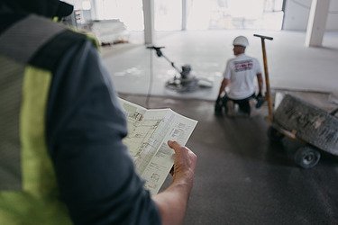 Foto einer Person von hinten mit einem Plan in der Hand 